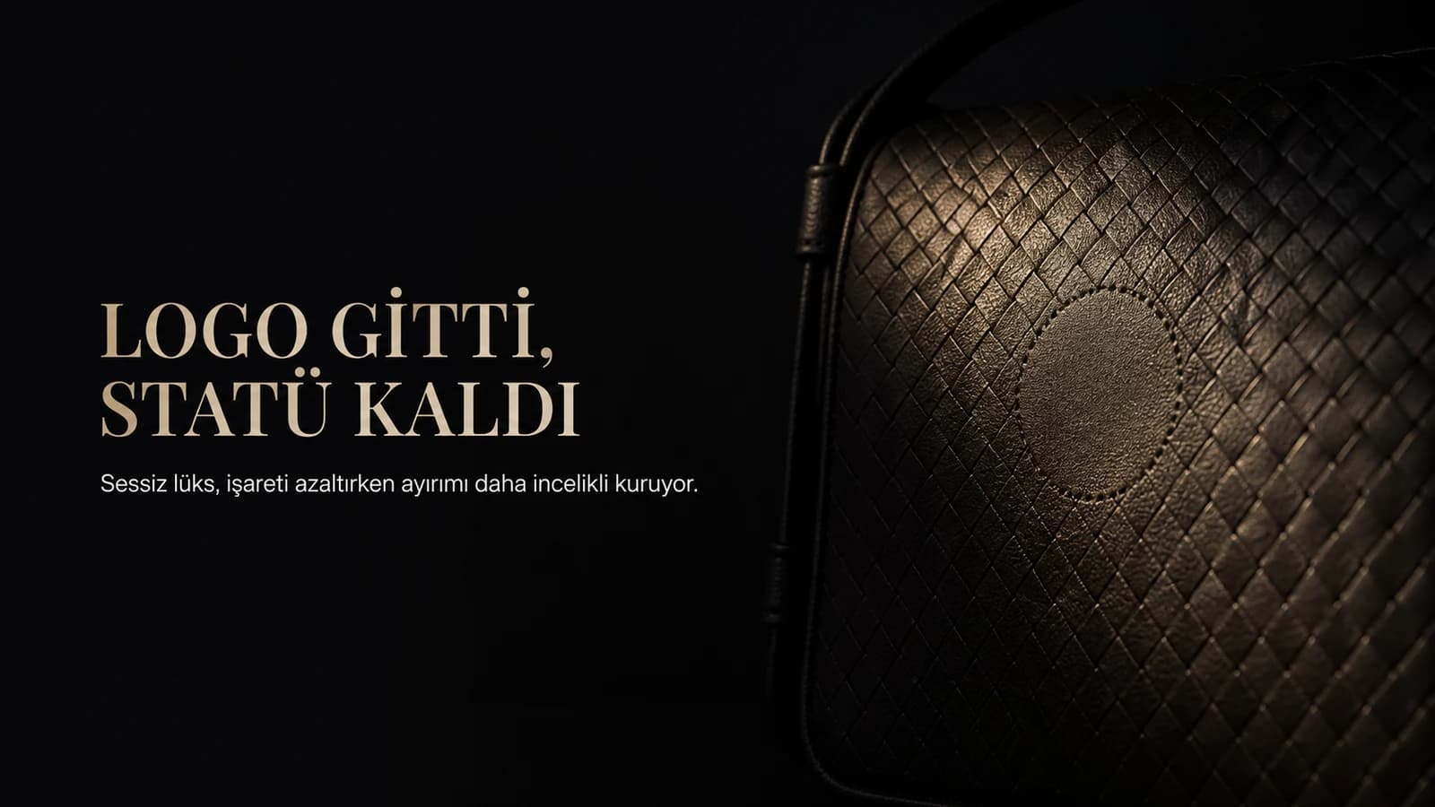 Koyu zeminde metal amblemi çıkarılmış siyah deri çantada kalan iz ve ışıkta beliren ince örgü dokusu